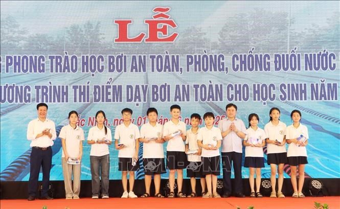 Ban tổ chức tặng trang phục bơi cho học sinh tại Chương trình thí điểm dạy bơian toàn.