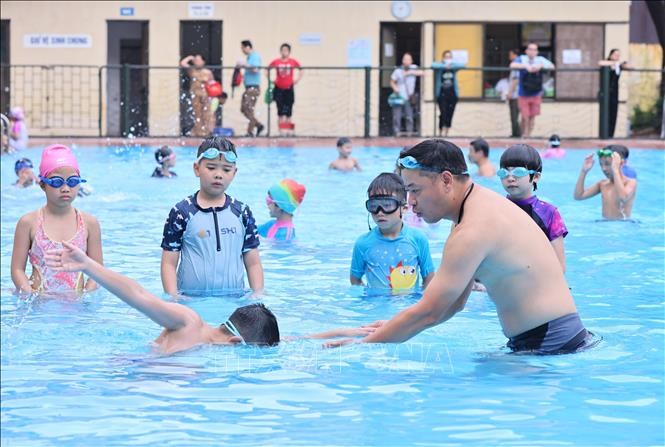 Huấn luyện viên hướng dẫn các động tác bơi đúng cách cho các em tại bểbơi Thái Hà. Ảnh tư liệu: Minh Đức/TTXVN
