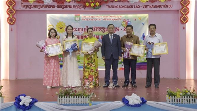 Đại sứ Việt Nam tại Lào Nguyễn Minh Tâm trao giấy khen cho Hội người Việt Namthủ đô Viêng Chăn và Ban giám Hiệu nhà trường. Ảnh: TTXVN phát