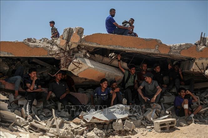 Người dân Palestine ngồi trên đống đổ nát ở khu vực Sudaniya, phía Bắc thành phốGaza. Ảnh: THX/TTXVN