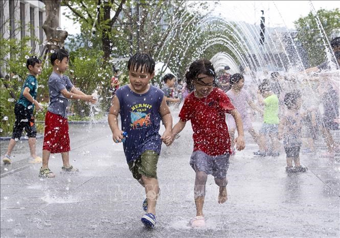 Các em nhỏ chơi đùa bên đài phun nước để tránh nóng, tại Seoul, Hàn Quốc. Ảnh:THX/TTXVN