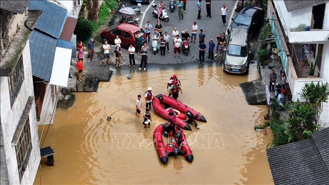 Lực lượng cứu hộ hỗ trợ người dân di chuyển qua vùng ngập lụt tại Khu tự trị dântộc Choang Quảng Tây, Trung Quốc. Ảnh: THX/TTXVN