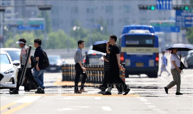 Người dân di chuyển trên đường phố dưới trời nắng nóng tại Seoul, Hàn Quốc. Ảnh:Yonhap/TTXVN