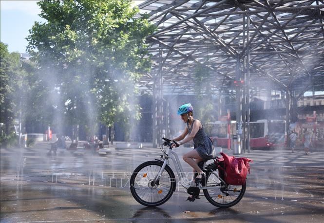 Người dân tránh nóng bên đài phun nước tại Vienna, Áo, ngày 3.7.2025. Ảnh:THX/TTXVN