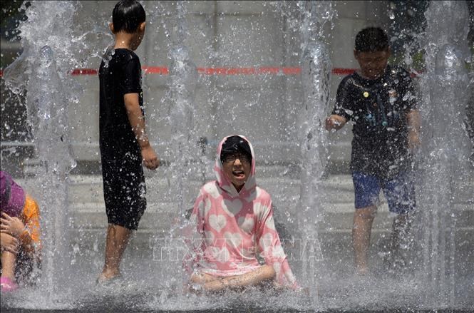 Các em nhỏ chơi đùa bên đài phun nước để tránh nóng tại Seoul, Hàn Quốc. Ảnh:Yonhap/TTXVN
