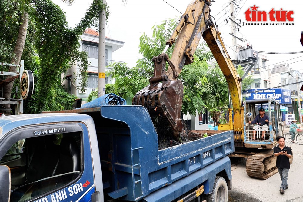 Ông Phạm Hữu Danh, Trưởng khu phố 26, phường An Phú Đông (mặc áo màu đen) đi hỗ trợ cho nhóm bạn trẻ dọn rác dưới lòng kênh.