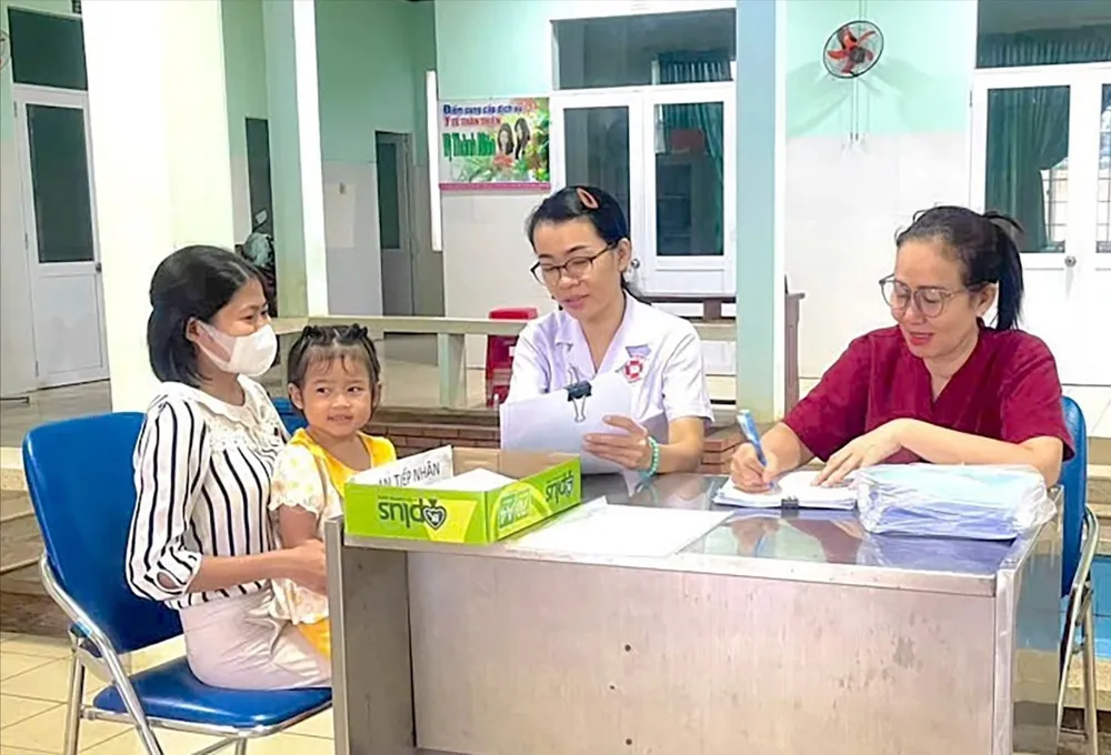 BS Lưu Thị Ngọc Hằng, Trưởng Trạm y tế phường Tam Long (thứ 2 từ phải sang), tư vấn sức khỏe cho người nhà bệnh nhi. Ảnh: TRÚC GIANG