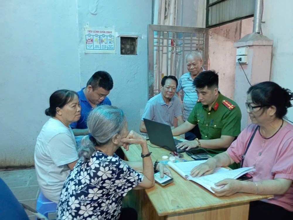 Công an phường Tây Hồ hướng dẫn cán bộ, đảng viên cài đặt ứng dụng thực hiện thủ tục hành chính Đảng. Ảnh: Quang Thái