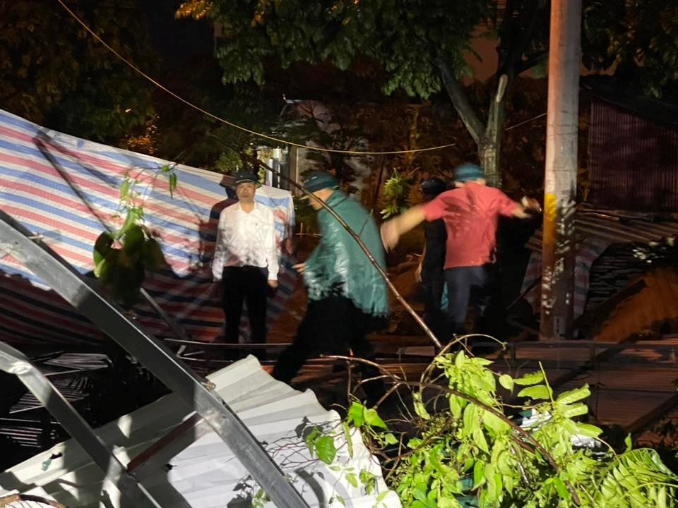 Lãnh đạo xã Hòa Lạc và các lực lượng chức năng xử lý cây bị đổ do ảnh hưởng của mưa dông chiều 19-7. Ảnh: Vũ Vân.