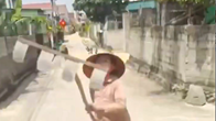 Người phụ nữ phơi lúa giữa đường cầm cào chặn đầu xe tải 