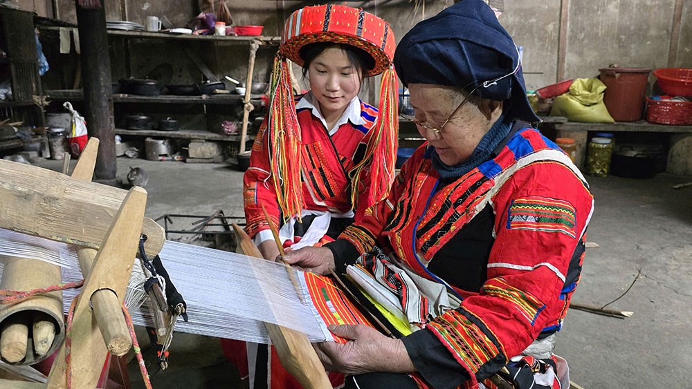 Nghệ nhân lớn tuổi hướng dẫn thế hệ trẻ kỹ thuật dệt thổ cẩm truyền thống tại bản làng vùng cao