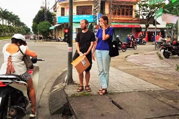 Hỗ trợ hai người nước ngoài cầm bảng xin cứu giúp trên đường phố - Anh 1